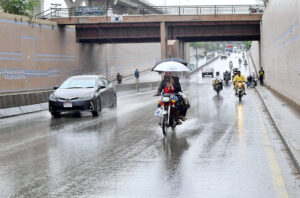 A family traveling on the motorcycle under the cover of umbrellas to protect from rain in the city