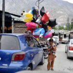A young vendor selling colorful balloons at roadside