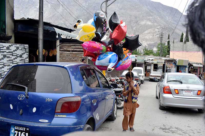 A young vendor selling colorful balloons at roadside