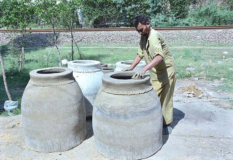An artisan busy in preparing traditional clay oven (tandoor) at his workplace.