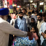 Volunteer distributing Iftar drink for deserving people outside his shop