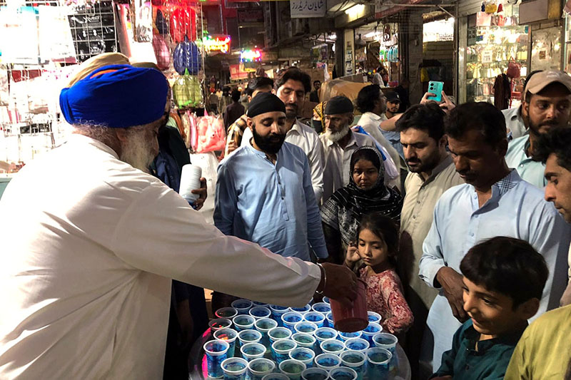 Volunteer distributing Iftar drink for deserving people outside his shop