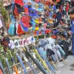 Vendor displaying caps and umbrellas to attract customers at roadside setup