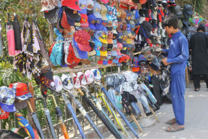 Vendor displaying caps and umbrellas to attract customers at roadside setup