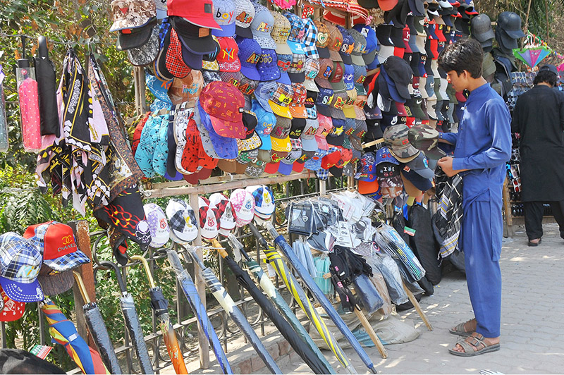 Vendor displaying caps and umbrellas to attract customers at roadside setup