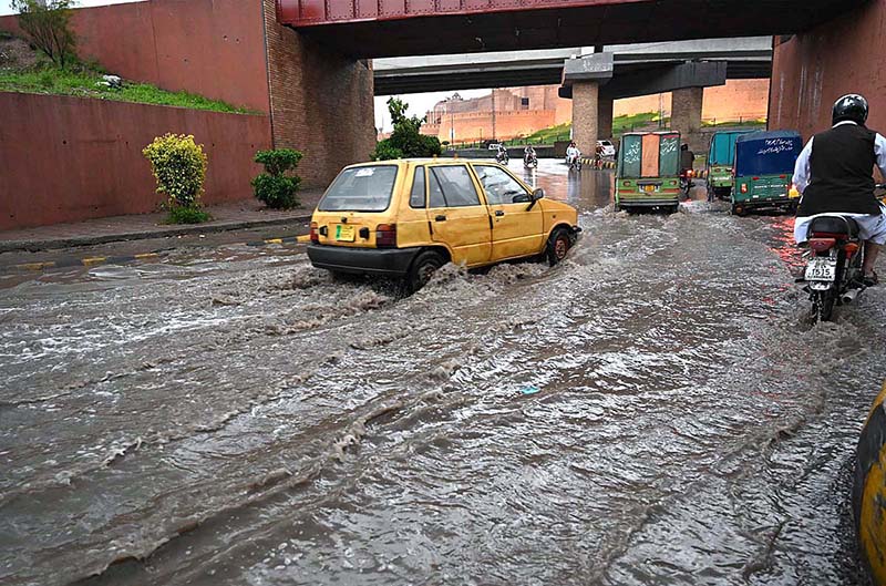 Vehicles passing through rain water accumulated on road in front of Radio Pakistan during heavy rain in the city.