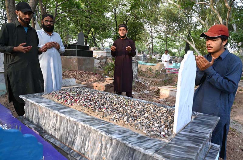 People offering Fateha on the graves of their family members in graveyard on the occasion of Eidul Fitr