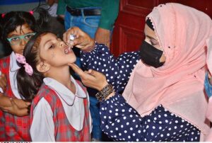 Polio worker administering polio drops to children at local school during anti-polio vaccination campaign in the city.