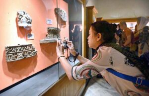 Chinese visitor taking pictures of displayed stuff with cell phone during visit to Peshawar Museum.