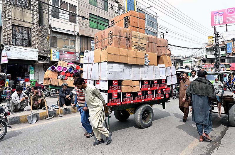 Labourers pulling hand cart heavily loaded with luggage to be delivered on different shops at Raja bazar.