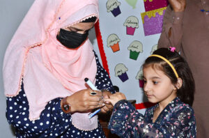 Polio worker administering polio drops to children at local school during anti-polio vaccination campaign in the city.