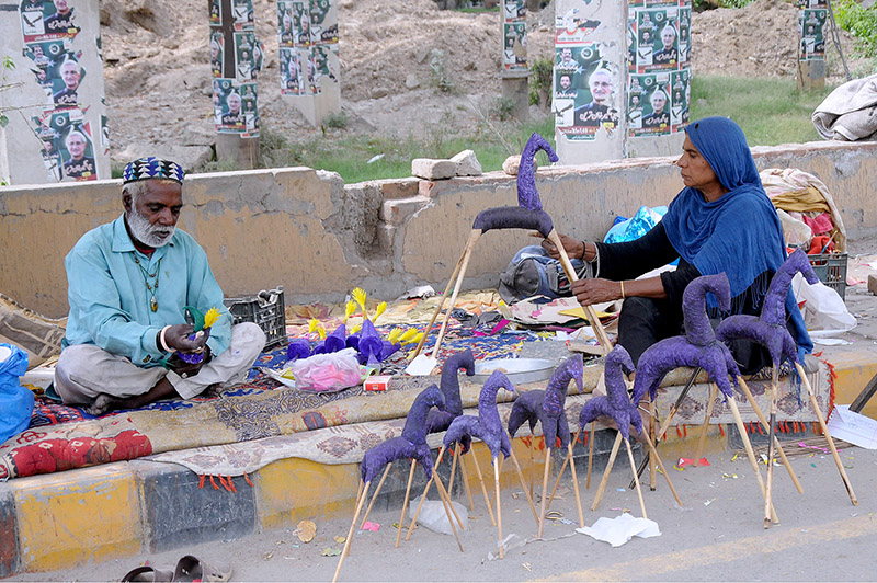 An elderly couple preparing handmade paper toys called