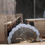 A worker is busy making a design on a wooden sheet with the help of a machine at his workplace