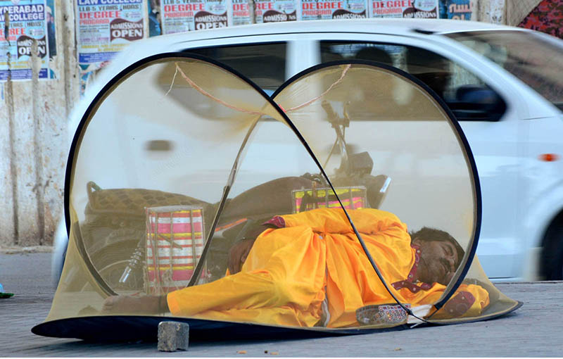 A person seeks nap under a mosquito net on the footpath at Wahdu Wah road