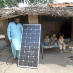 A man fixing a solar penal at his makeshift hut
