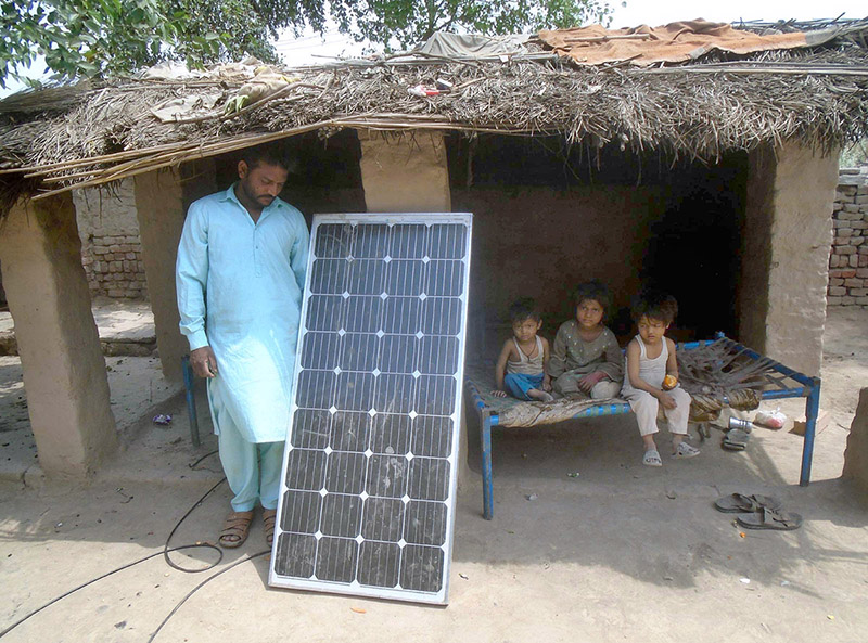 A man fixing a solar penal at his makeshift hut