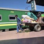 Laborer carrying passenger’s luggage on loader to load on train at Railway Station