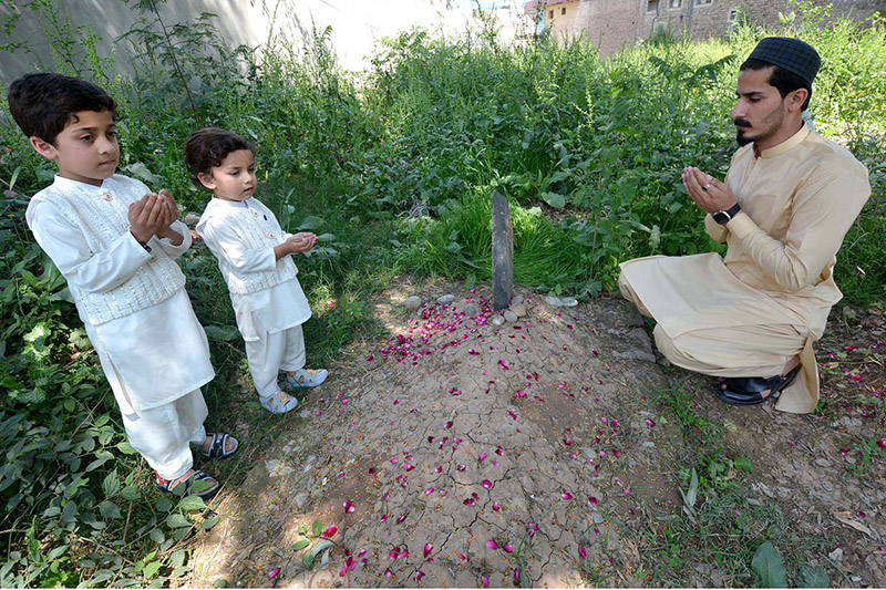 People showering flower petals on graves of their family member on the occasion of Eid ul Fitr.