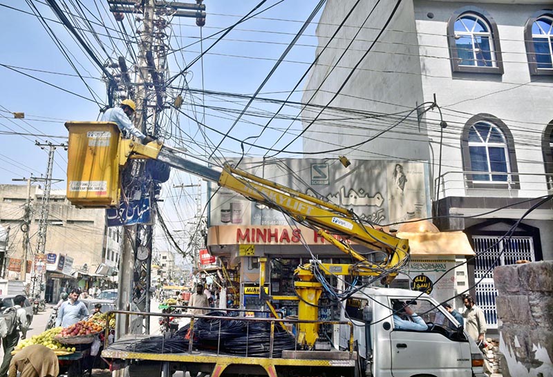 IESCO staffer installing new electric cables on pole at Minhas chowk in the city.