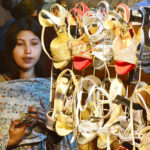 A girl busy in selecting and purchasing sandals from vendor in preparation of upcoming Eid ul fitr at a market