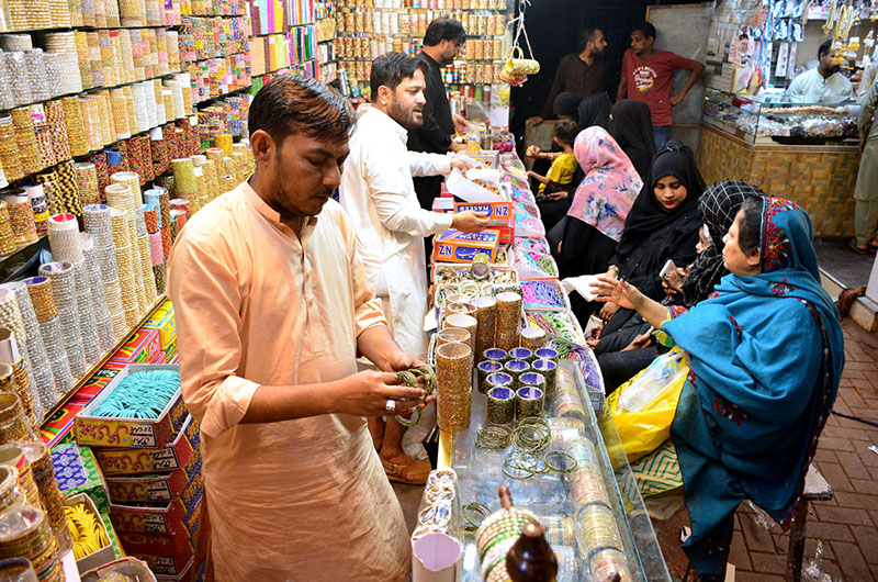A girl busy in selecting and purchasing sandals from vendor in preparation of upcoming Eid ul fitr at a market