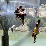 Youngsters jumping for bathing in water canal to get relief from hot weather in the city.