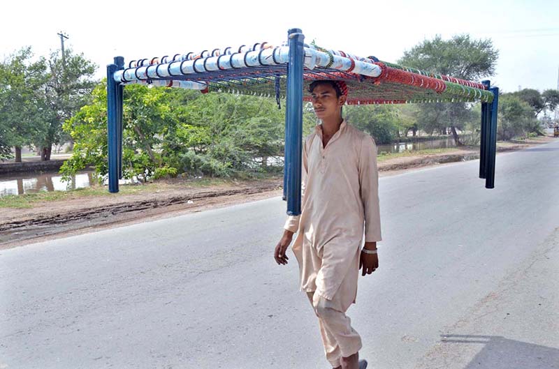 A person on the way carrying traditional bed (Charpai) on his head