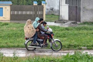 A woman along with children on the way during rain at Tarlahi in the Federal Capital.