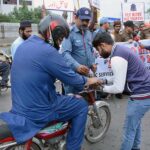 A traffic police personnel installing a kite string protector on a motorcycle for safety measure