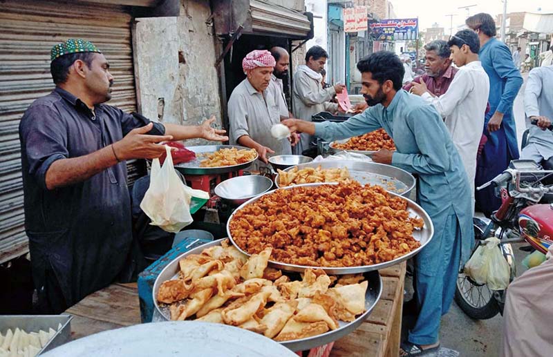 In the Islamic fasting month of Ramzan, people are buying Samose and Pakoray from a roadside stall.