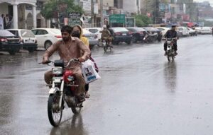 A motorcyclist along with his daughter on the way under the cover of an umbrella to protect from rain that experienced the city.