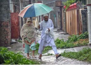 A woman along with children on the way during rain at Tarlahi in the Federal Capital.
