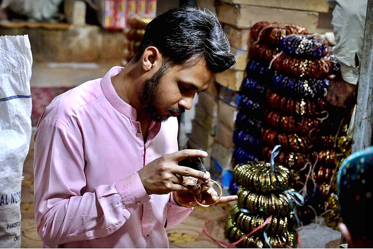 Worker giving final touch to bangles at their workplace during upcoming Eid-ul-Fitr at Bangle Market.