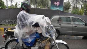 A woman along with children on the way during rain at Tarlahi in the Federal Capital.