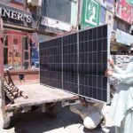 A man busy loading solar panel on loader tricycle after purchasing near Shaheen Chowk