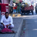 Vendor preparing garlands to attract customers at roadside