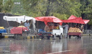 A woman along with children on the way during rain at Tarlahi in the Federal Capital.