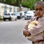 A gypsy youngster on the way while carrying bread (roti) which distributed by volunteer.