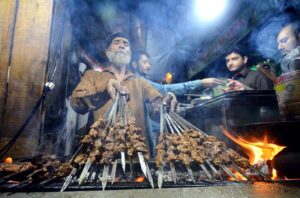 Vendor preparing traditional food item Tikkay for customers at Fawara Chowk during Ramadan.