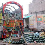 Labourers off-loading watermelons from a delivery truck at the fruit market