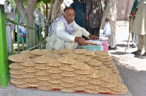 A vendor displaying and selling pigeons' food to attract customers at his roadside setup.