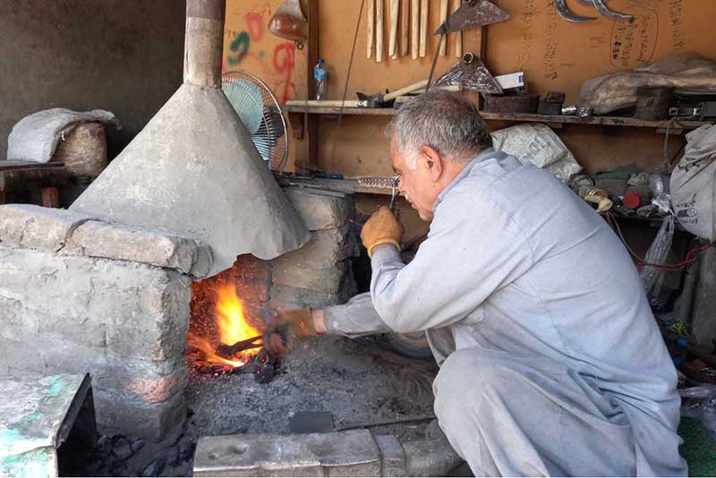 A blacksmith busy in making saw in traditional way on his work place at River view road