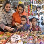 Women with children purchasing artificial jewelry during Eid shopping in preparation of upcoming Eid-ul-Fitr