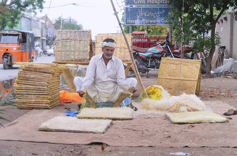 A worker preparing khas for the air cooler at his workplace