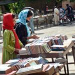 Women selecting old books from a roadside stall at Mall Road