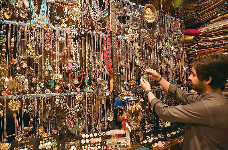 A shopkeeper is attracting customers in the upcoming Eid-ul-Fitr by showcasing women's favorite artificial jewelry products.