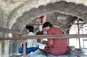Talented painter applying artwork to bring life on the historical wall of Daulat Khana at Shahi Qilla.