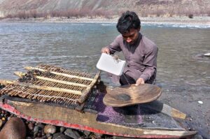 youngster searching for alluvial gold through a traditional way on the bank of river.