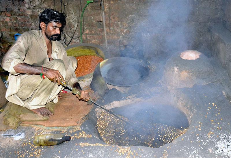 worker busy in roasting grams at his workplace.
