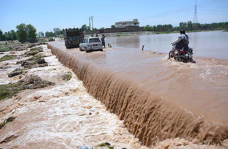 Vehicles passing through flood water at Bara Hazar Khuwani bridge after heavy rain in Provincial Capital.